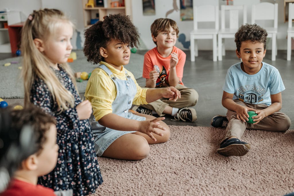 Happy children sitting together on a rug during a kindergarten class activity indoors.